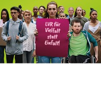 Gruppe aus Menschen verschiedenen Alters und Herkunft, Person in der Mitte der Gruppe h&auml;lt ein Plakat hoch mit den Worten "LVR f&uuml;r Vielfalt statt Einfalt"