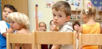 Ein Junge sitzt in einer Kindertagesbetreuung auf einem Stuhl