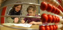 M&auml;dchen mit Lehrerin vor einem &Uuml;bungsblatt